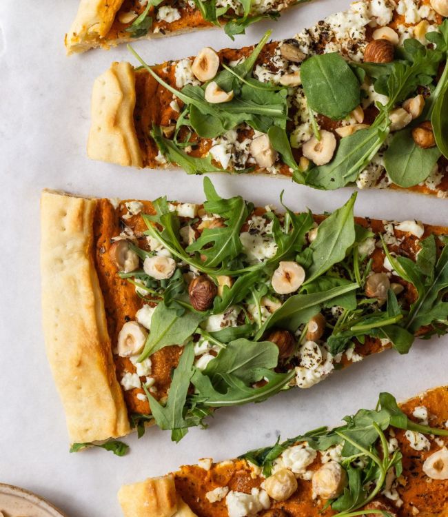 Pizza con crema di peperoni, formaggio greco, rucola e nocciole